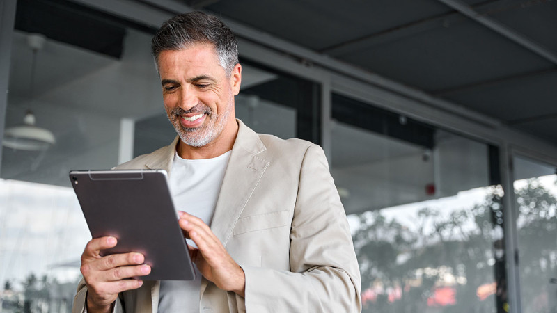 Man smiling while using a tablet computer